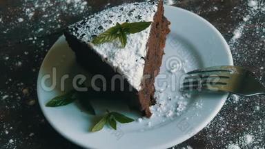 一块巧克力蛋糕放在白色盘子上，旁边放着新鲜的薄荷叶